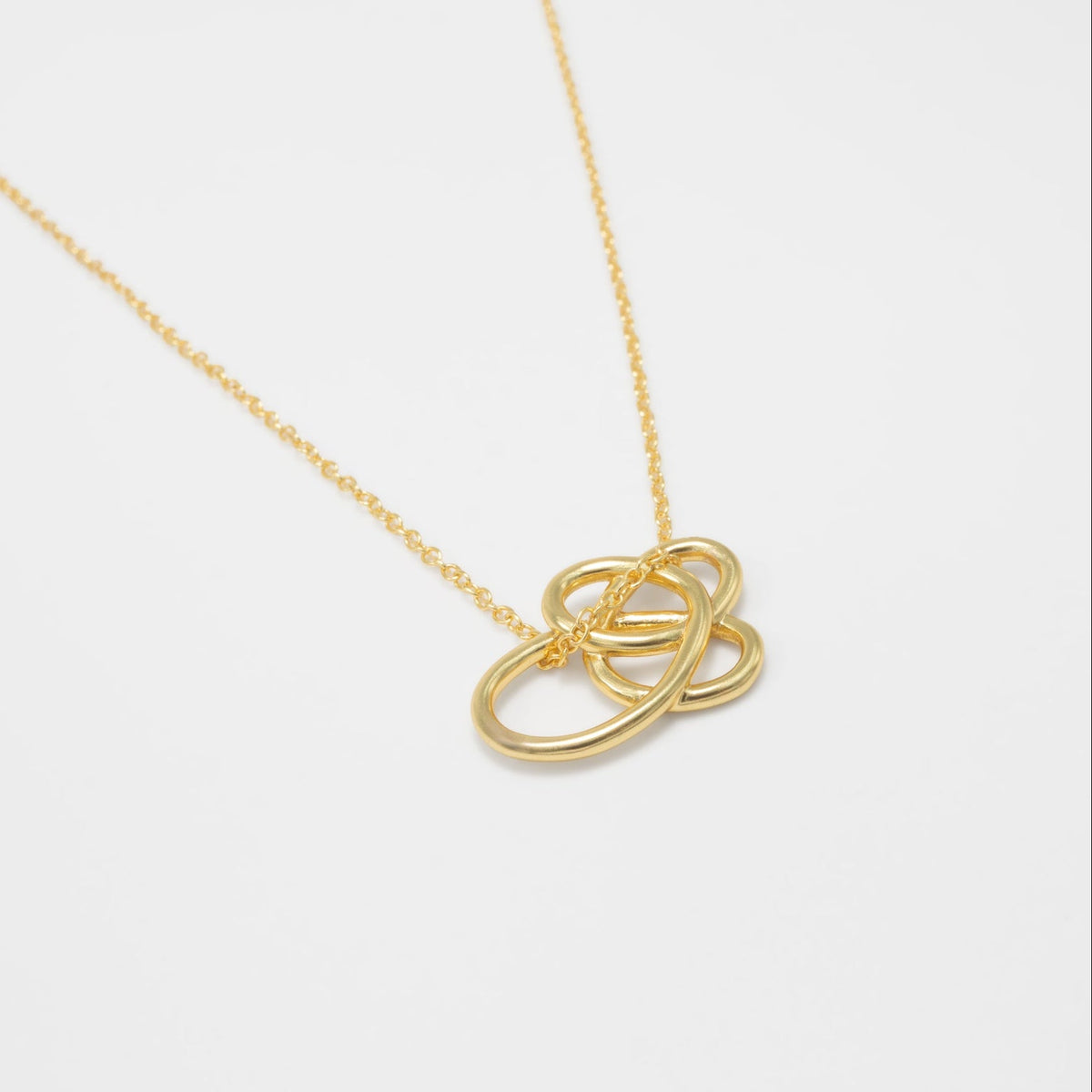 Gold necklace with a Celtic knot pendant on a white background