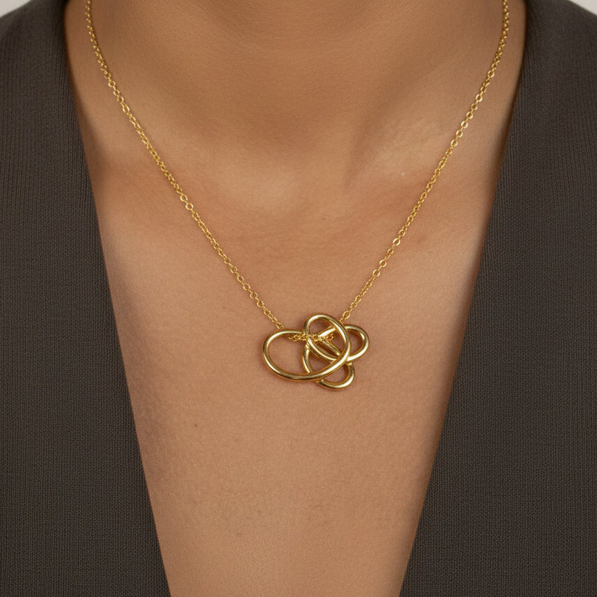 Gold necklace with a intricate pendant on a person's neck