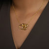 Woman wearing a gold necklace with a scribbled wire pendant