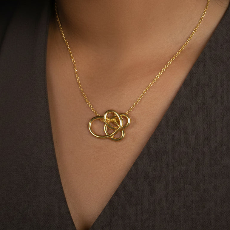 Woman wearing a gold necklace with a scribbled wire pendant