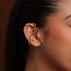 Gold ear cuff worn by a women with a blurred background