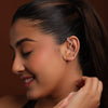 Woman wearing a silver earcuff against a brown background