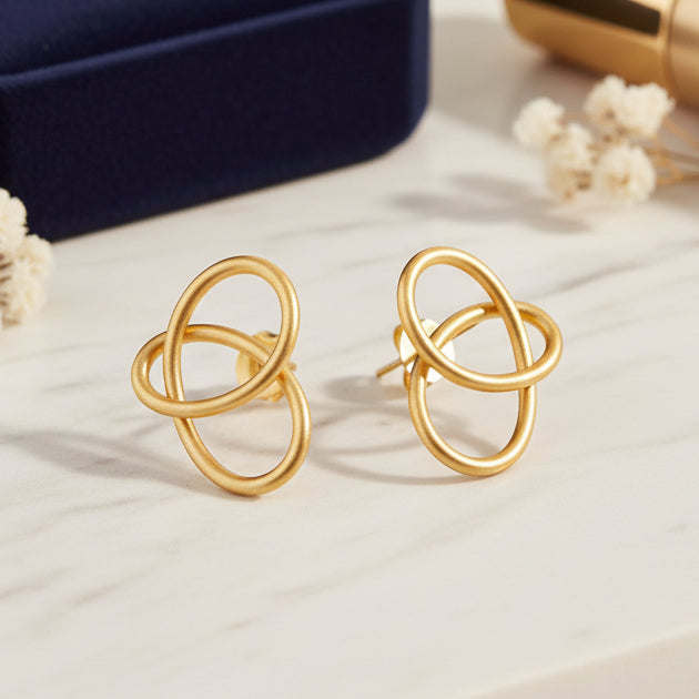 Pair of gold earrings on a light gray background