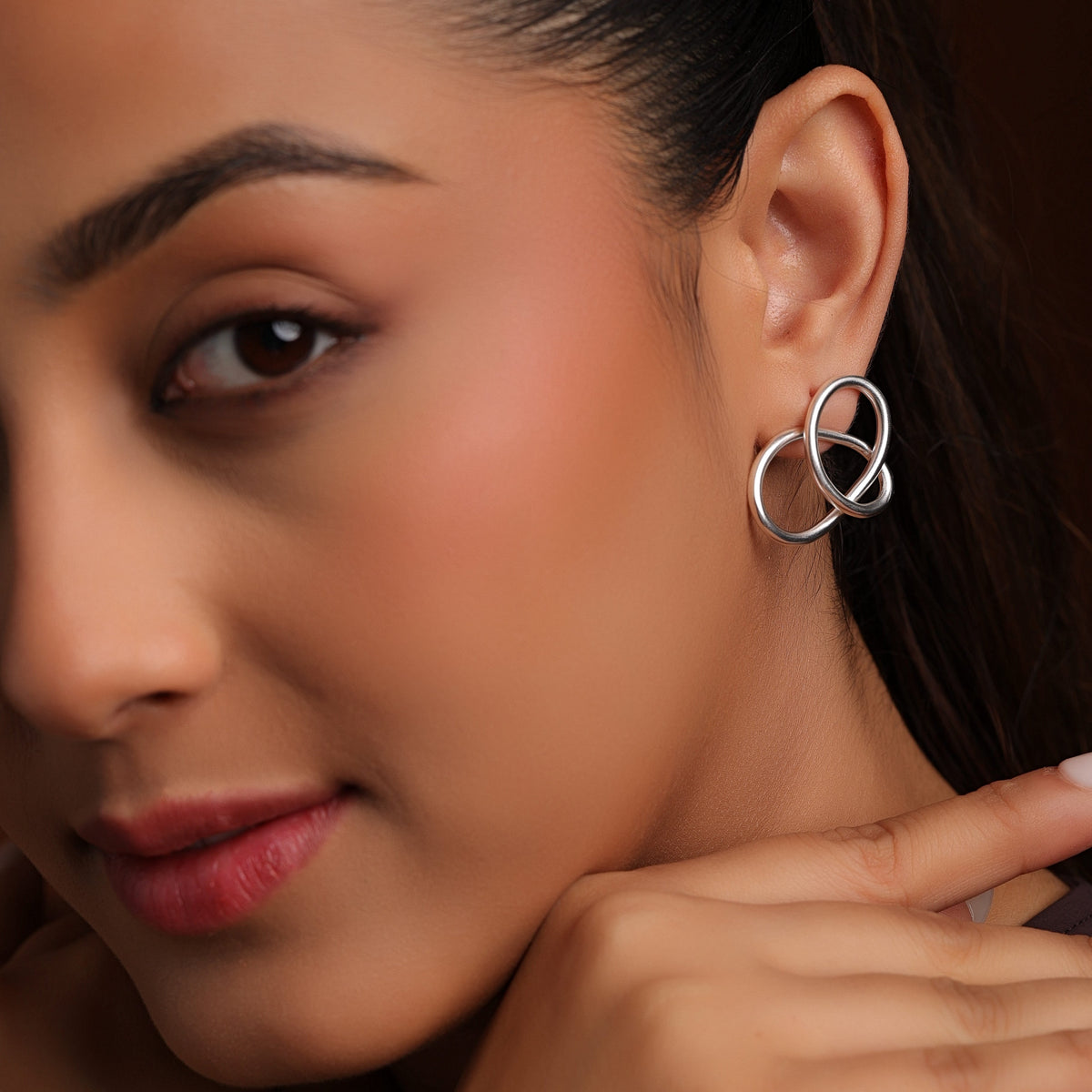 Close-up of a woman wearing a silver earring with a dark background