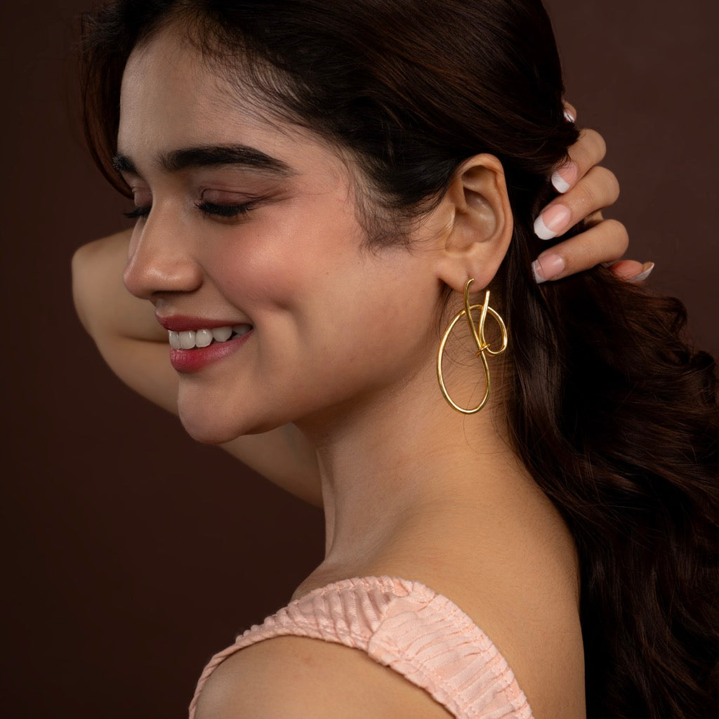 Woman wearing gold hoop earrings with a blurred background