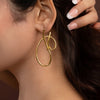 Gold hoop earring worn by a person with a neutral background