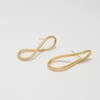 Gold earrings on a light gray background