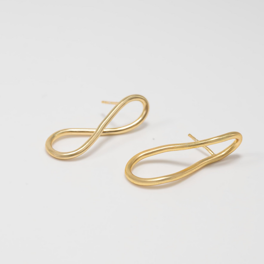 Gold earrings on a light gray background