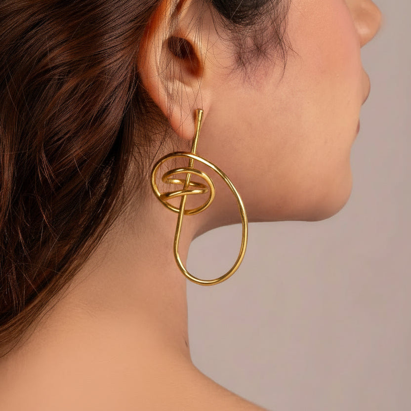 Gold earring worn by a person with a neutral background