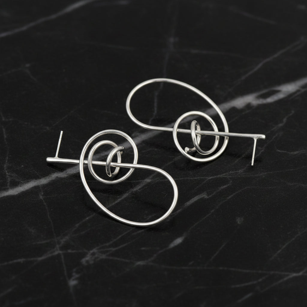Pair of silver earrings on a black marble background