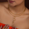 Gold necklace on a person wearing an orange top with a blurred background