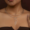 Gold necklace with a unique design worn by a person against a brown background