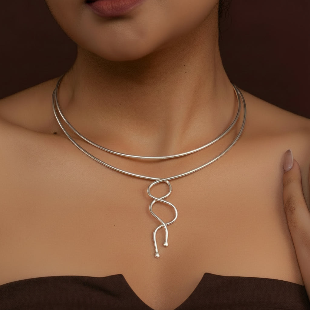 Gold necklace with a unique design worn by a person against a brown background