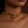 Gold choker necklace worn by a person with a brown background