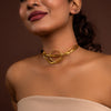 Woman wearing a gold necklace against a brown background