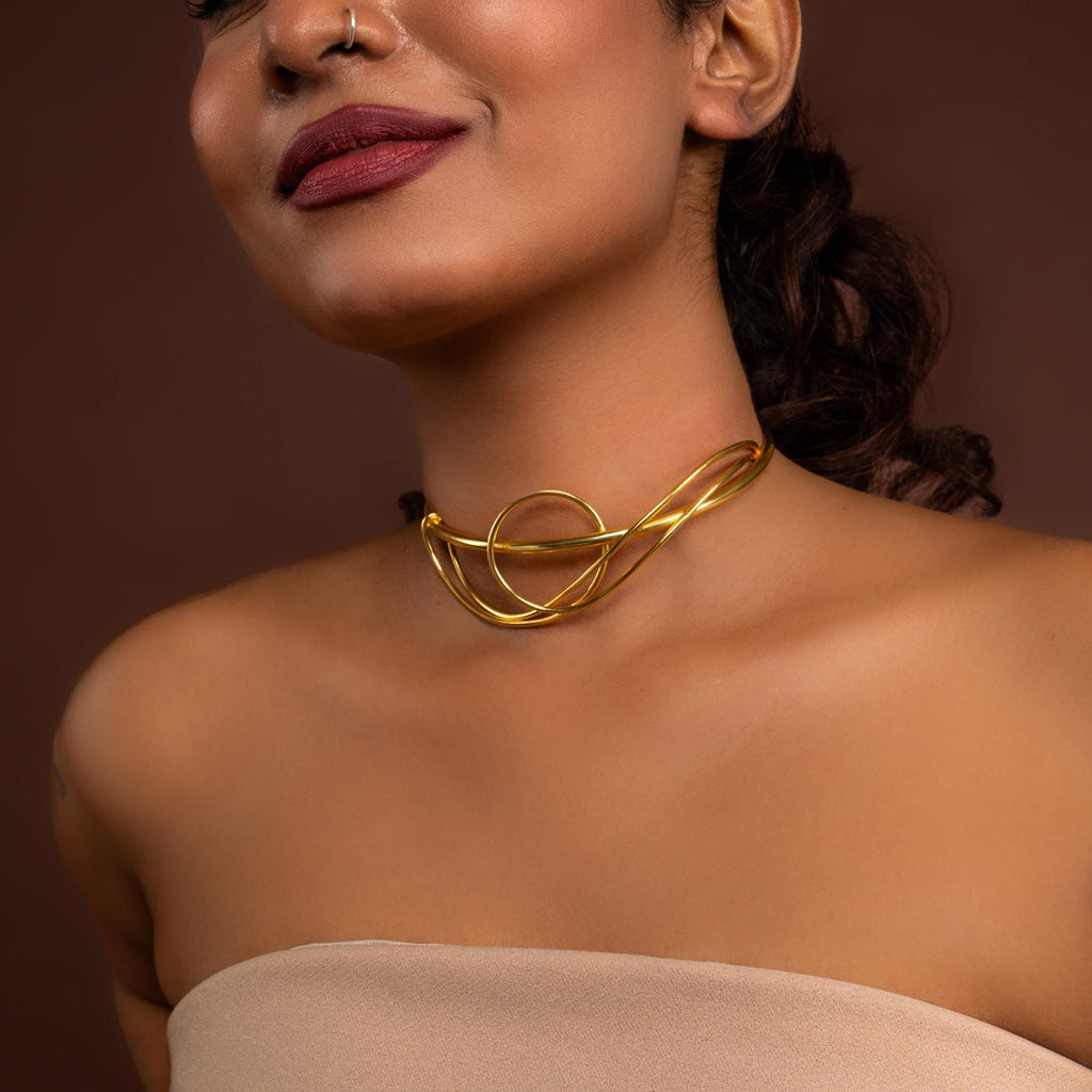 Woman wearing a gold necklace against a brown background