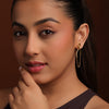 Woman wearing gold earrings with a brown background