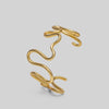 Gold abstract bracelet on a light gray background
