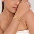 Woman wearing a gold bracelet on a plain background