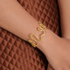 Gold bracelet on a person's wrist against a brown textured background