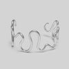 Silver abstract bracelet on a light gray background