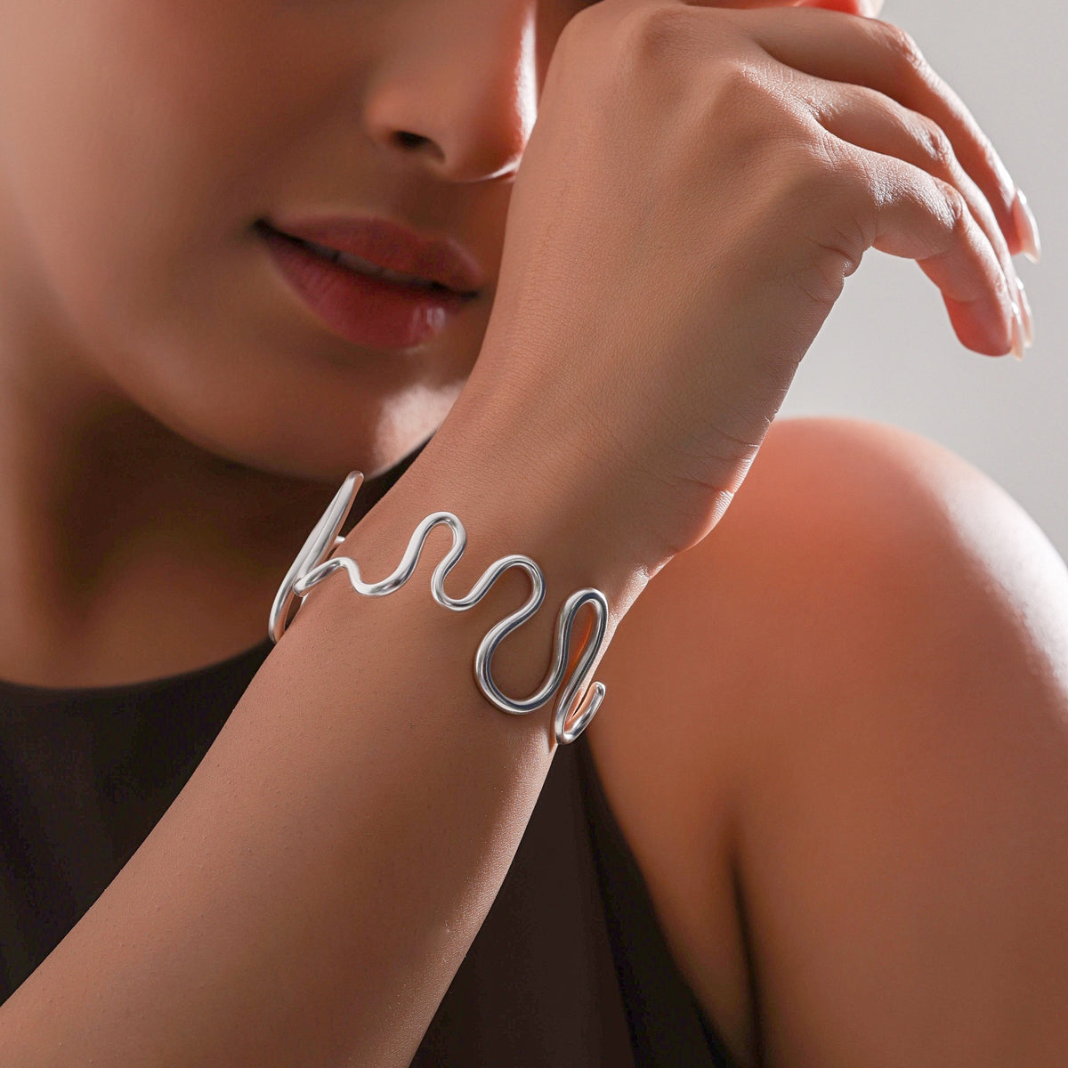 Woman wearing a silver bracelet with a neutral background