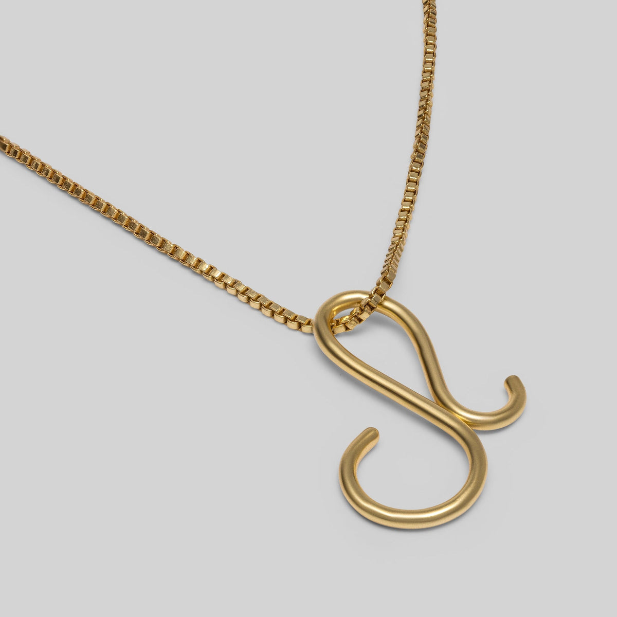 Gold necklace with a unique pendant on a light gray background