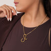Woman wearing a gold necklace with a pendant against a neutral background