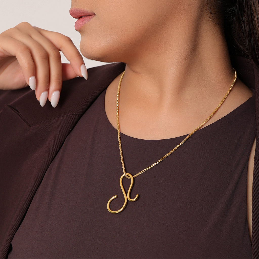 Woman wearing a gold necklace with a pendant against a neutral background