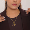 Woman wearing a gold necklace with a pendant against a neutral background