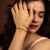 Woman wearing a gold bracelet on her wrist with a soft focus background