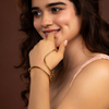 Woman with gold bracelet on a brown background