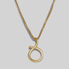 Gold necklace with a unique round pendant on a grey background