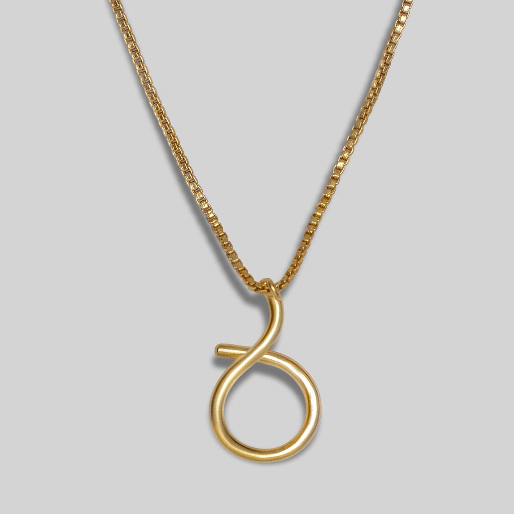 Gold necklace with a unique round pendant on a grey background