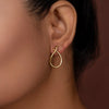Gold tiny earring worn by a person against a neutral background
