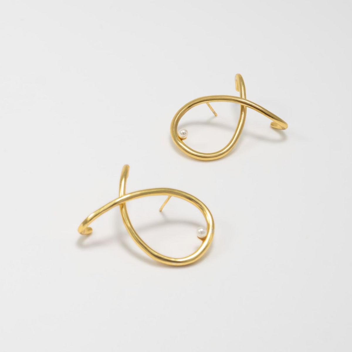Pair of gold earrings on a light gray background