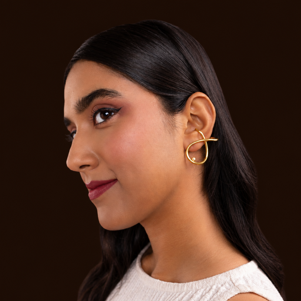 Woman wearing gold earrings against an orange background