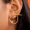 Gold ear cuff with a pearl on an ear against an orange background